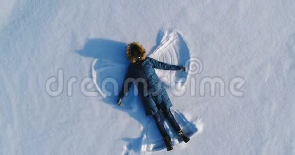 女人让雪天使躺在雪地里空中录像照相机慢慢地移开视频的预览图
