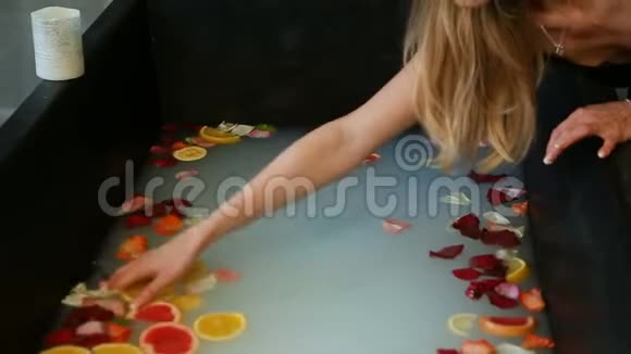 从女人身上取出混合柑橘片和玫瑰花瓣的水视频的预览图
