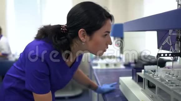 描绘年轻的实验室妇女穿着蓝色制服和橡胶手套控制实验室的药物制造开展活动视频的预览图