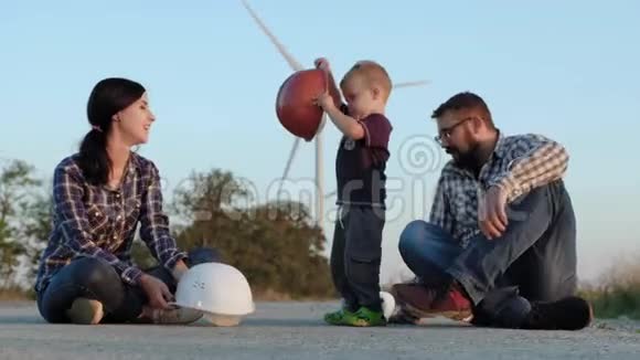 幸福的家庭坐在路上一个孩子玩建筑头盔亲吻母亲和五岁的父亲视频的预览图