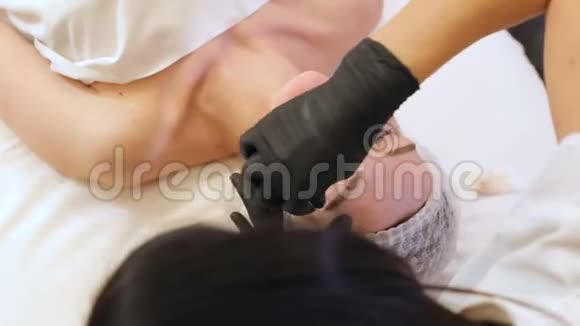 美容师在水疗中心用棉签擦拭一个年轻女孩的脸视频的预览图