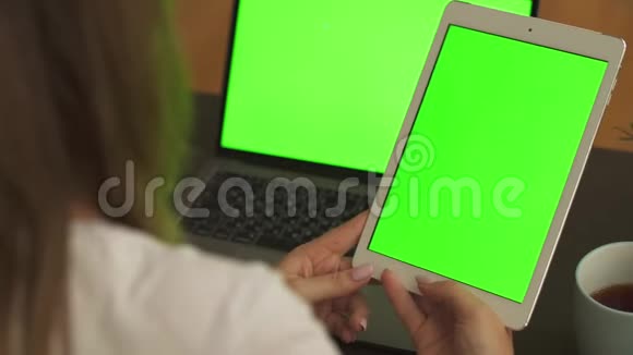 用绿色屏幕在平板电脑上打字的女性手的特写镜头女性在工作场所使用带有绿色显示器的笔记本电脑视频的预览图