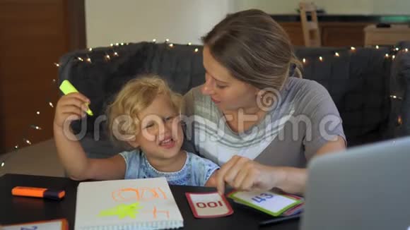 教师家教和一个小女孩在桌子上的老师或妈妈家庭教育概念视频的预览图