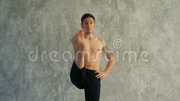 男瑜伽大师在工作室伸展腿站着手里握着一条腿视频的预览图