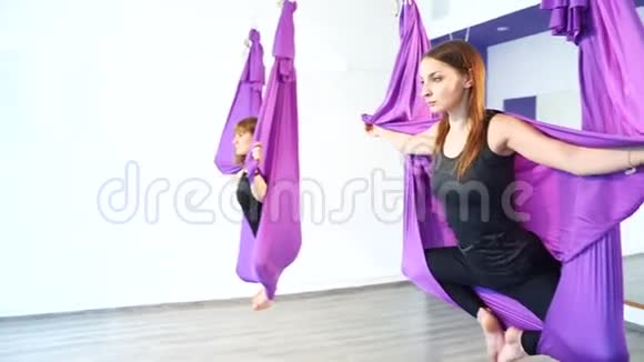 空中瑜伽课年轻女子在吊床上练习瑜伽视频的预览图