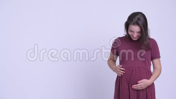 快乐的年轻美丽的孕妇向后面展示一些东西视频的预览图