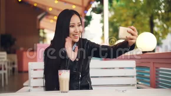 快乐的亚洲女士正在与朋友在线交谈用智能手机独自坐在露天咖啡馆里打视频电话女孩是视频的预览图