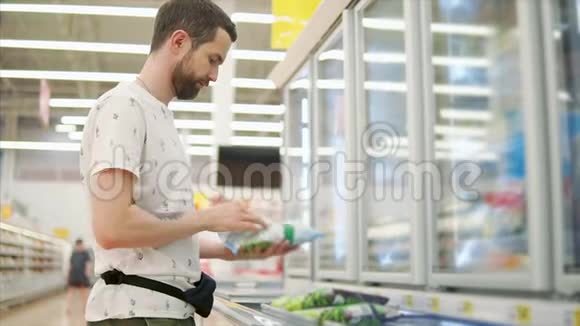 年轻人正在超市大厅里检查一包冷冻蔬菜视频的预览图