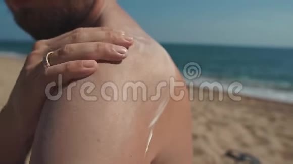 男性度假者正在擦肩在海滩上涂抹防晒霜特写镜头视频的预览图