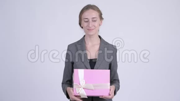一位年轻的金发女商人抱着礼品盒思考着视频的预览图