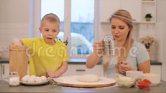 可爱的小男孩和他漂亮的妈妈穿着五颜六色的衬衫一边玩耍一边笑一边揉着面团视频的预览图