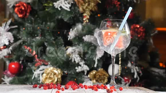 新年和圣诞快乐的餐桌概念杯子里放一杯鸡尾酒里面放一根稻草背景是一棵毛皮树视频的预览图
