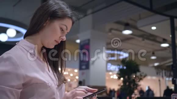 电子商店女性顾客在橱窗附近挑选和测试现代智能手机视频的预览图
