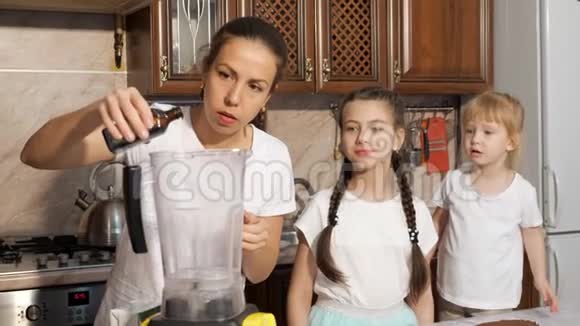 妈妈正在厨房里和她的女儿们用搅拌机做奶油视频的预览图