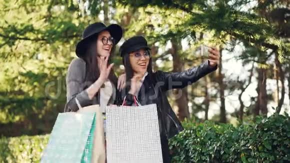 兴奋的女孩正在使用智能手机手持设备进行在线视频通话并展示购物袋视频的预览图