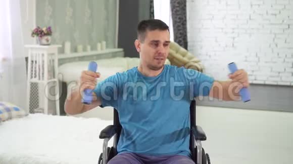 坐轮椅的残疾人在家用哑铃训练慢动作视频的预览图