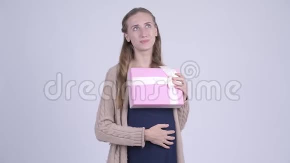 幸福的年轻孕妇抱着礼物盒思考视频的预览图