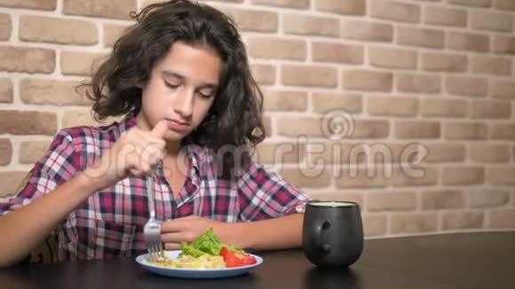 饥肠辘辘胃口大开的少年男孩吃法法勒在厨房里用阁楼式的意大利面弓靠在砖墙上视频的预览图