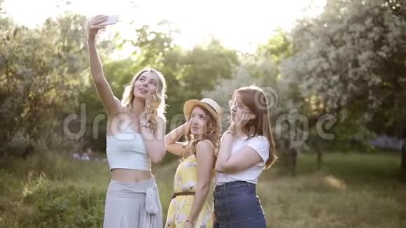 正面看三位年轻女性用手机自拍摆姿势女孩们花时间在花园里户外轩轩视频的预览图