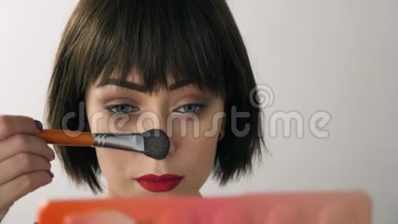 美丽的女孩在镜子前化妆视频的预览图