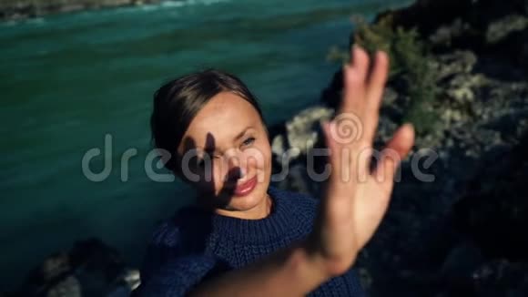穿毛衣的漂亮女孩用手看太阳手影在她脸上视频的预览图