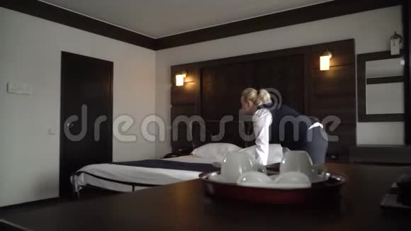女佣在一间舒适的小旅馆房间里铺一张双人床视频的预览图