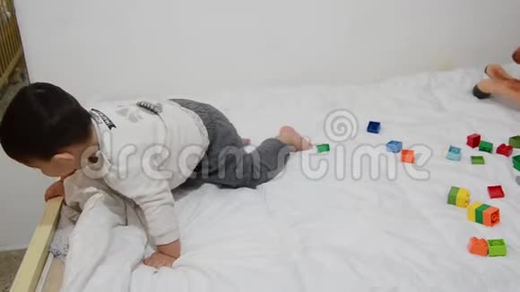 一个半岁的男孩在床上玩乐高积木和软玩具视频的预览图