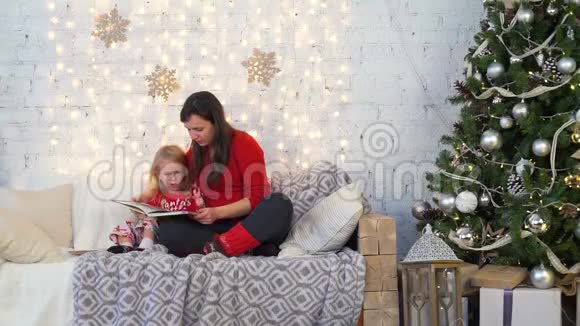 母亲和女儿在圣诞节读一本书视频的预览图