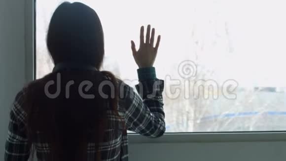 伤心沮丧的年轻女子透过窗户视频的预览图
