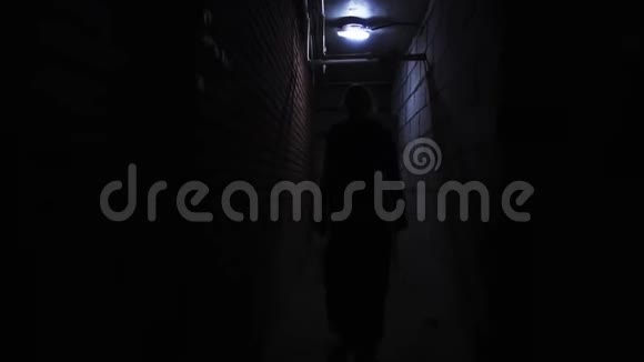 女人在黑暗阴暗的地下室走廊里移动视频的预览图