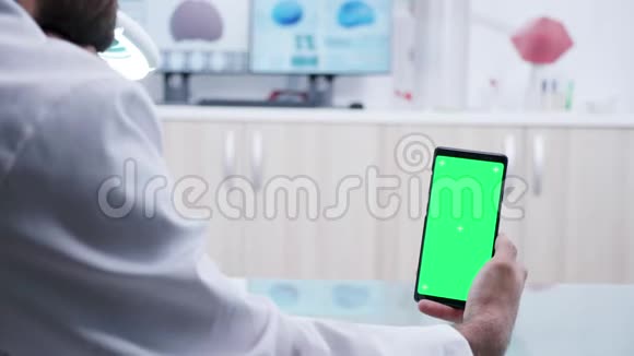双手握着绿色屏幕的智能手机放大镜头视频的预览图