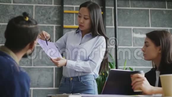 年轻的亚洲女性在现代创业办公室向同事展示房屋的纸质建筑方案视频的预览图