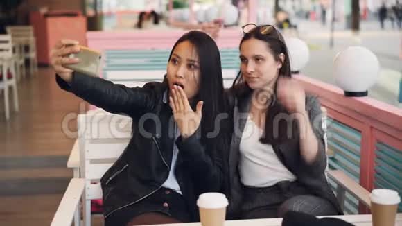 漂亮的年轻女人正在咖啡馆里自拍坐在桌子上用智能手机可爱的白人女孩视频的预览图