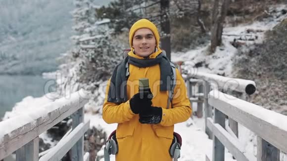 一个穿着冬装手里拿着热水瓶的年轻帅哥的肖像冬天穿黄色衣服的人视频的预览图