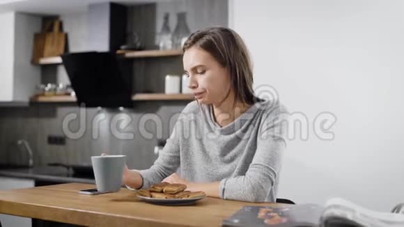 年轻活泼的黑发女孩在家吃煎饼喝茶做早餐视频的预览图