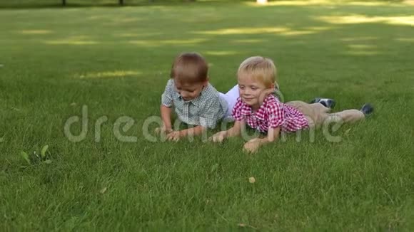 两个小男孩躺在公园的草地上他们撕下草扔了它视频的预览图