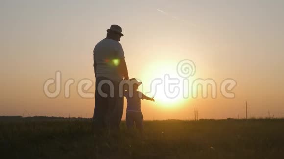 两代人的剪影一个成熟的祖父和小孙子在日落时玩耍视频的预览图