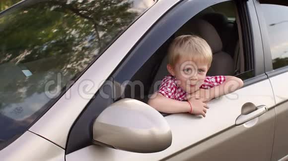一个快乐的小男孩坐在汽车的车轮后面竖起大拇指视频的预览图