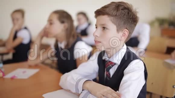 穿着校服的高中生坐在教室里专心听讲座视频的预览图