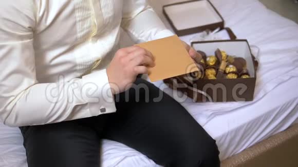 一个男人坐在旅馆的床上从信封里读到一封信视频的预览图