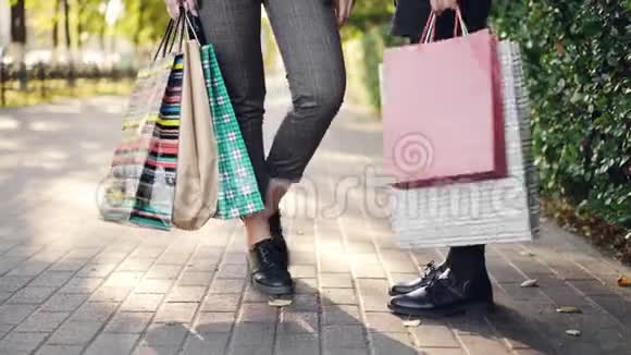 低角度拍摄的女性腿站在人行道上拿着购物袋后快乐的忙碌一天在商店和商场人民视频的预览图