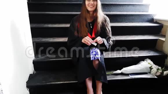 在大学里一位漂亮的学生硕士在坐在金属台阶上时用橡皮泥给她的腿贴上带子视频的预览图