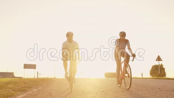 一男一女骑着自行车在日落时分一起慢悠悠地沿着公路行驶这对夫妇骑自行车旅行视频的预览图
