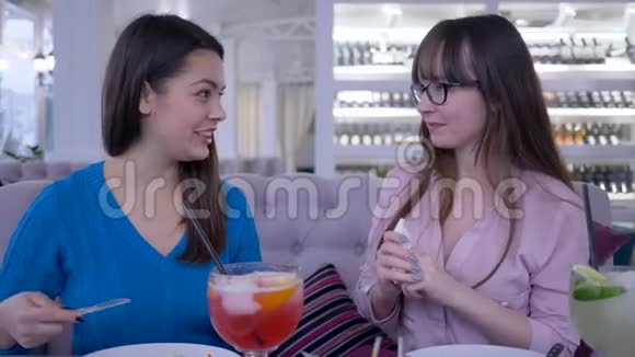 在咖啡馆里吃饭的时候年轻女性用叉子和刀子交流和切沙拉视频的预览图