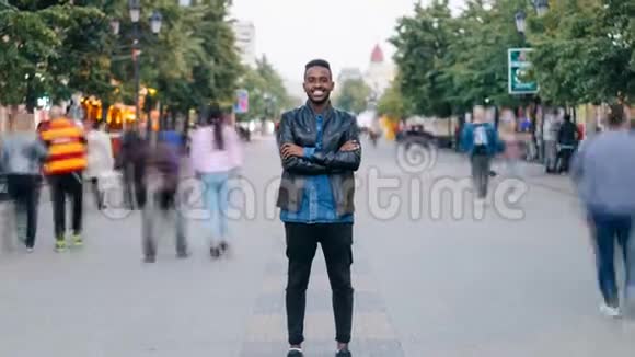 在市中心的街道上一个穿着牛仔裤和皮夹克的快乐非裔美国人慢慢消失了视频的预览图