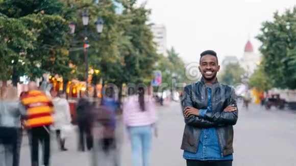 微笑的非裔美国人独自站在市中心双手交叉着享受城市生活和视频的预览图