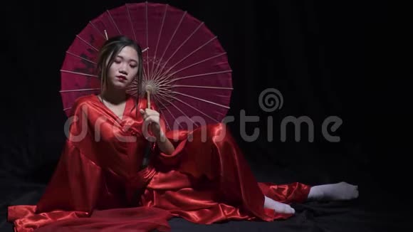 优雅的年轻女子穿着日本民族服装玩转纸伞微笑着视频的预览图