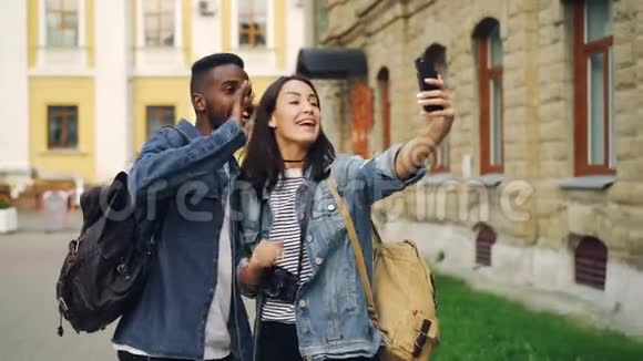 令人兴奋的游客男人和女人正在用智能手机手持设备进行在线视频通话并说话时竖起大拇指视频的预览图
