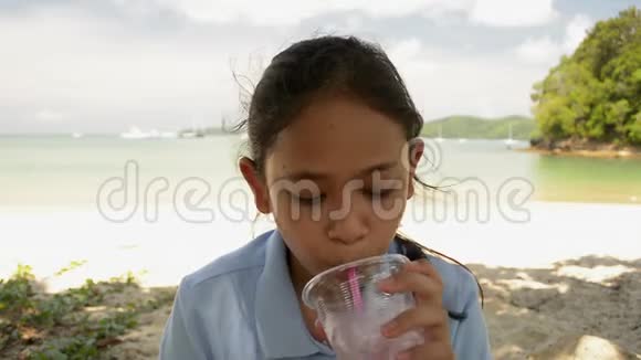 可爱的女孩正在用塑料杯里的吸管喝水视频的预览图