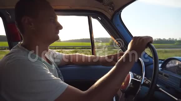 年轻人手握方向盘驾驶一辆带有太阳耀斑的复古汽车高加索人视频的预览图
